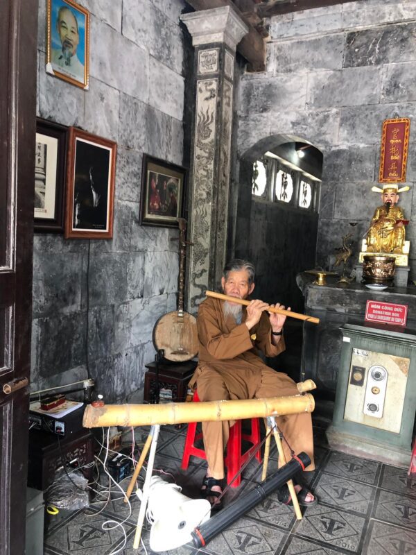 80 years old man playing traditional musical instrument at Thai Vi temple